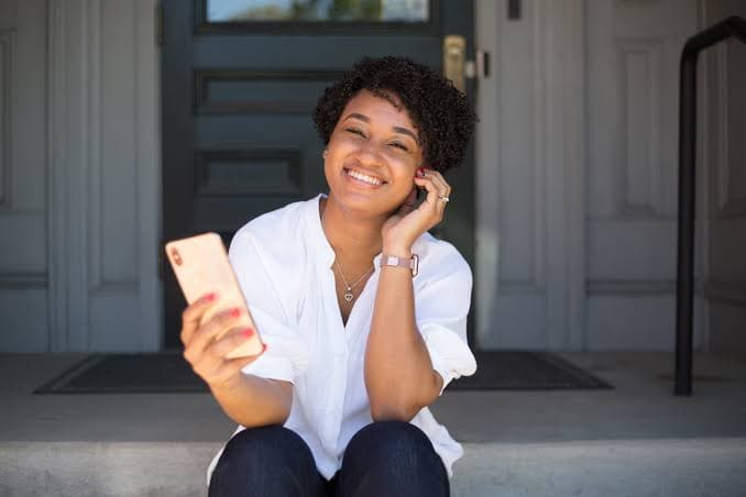 A person seated on a doorstep, looking to camera