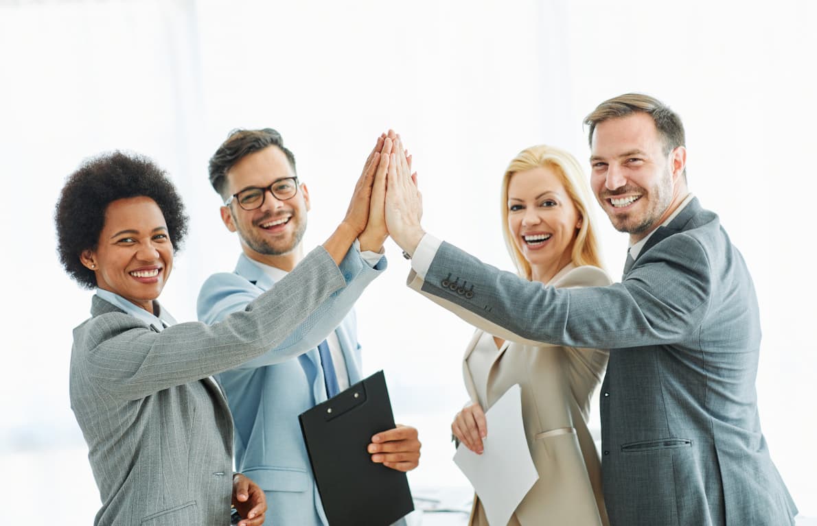 A team of four joining hands above a meeting table